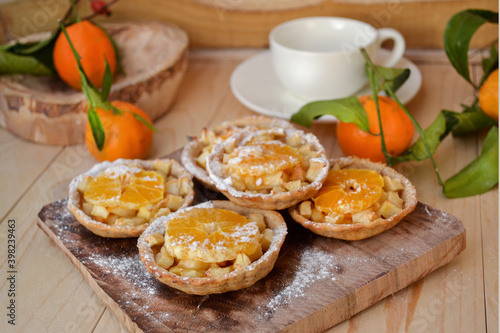 Mini fruit tarts with caramelized apple and tangerine. Homemade baking. Rustic style.