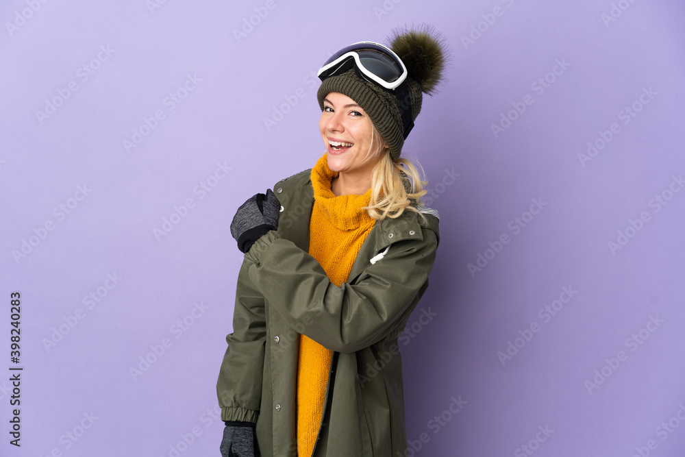 Skier Russian girl with snowboarding glasses isolated on purple background celebrating a victory Skier Russian girl with snowboarding glasses isolated on purple background celebrating a victory