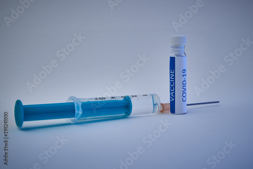 Close up of a vial with vaccine and a syringe on a white background. Close up of a flask with Covid-19 vaccine and a syringe. photo