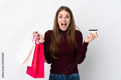 Young woman over isolated white background holding shopping bags and surprised
