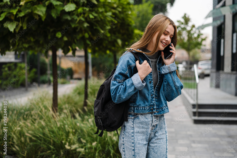 Beautiful happy student girl smiling and talking on mobile phone