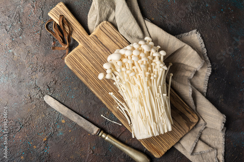 Fresh golden needle mushroom or enoki on wooden cutting board with vintage knife photo