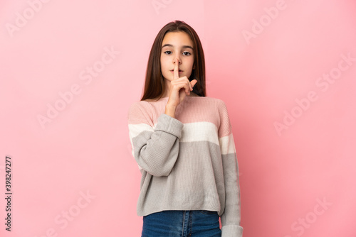 Little girl isolated on pink background showing a sign of silence gesture putting finger in mouth