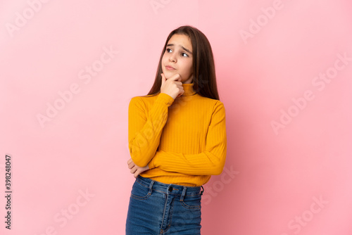 Little girl isolated on pink background having doubts