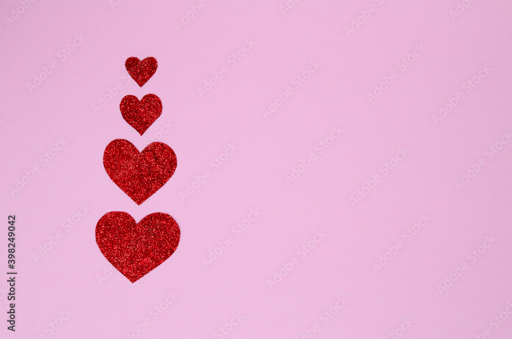 Four shiny red hearts on a pink background with copy space. Valentine's day.