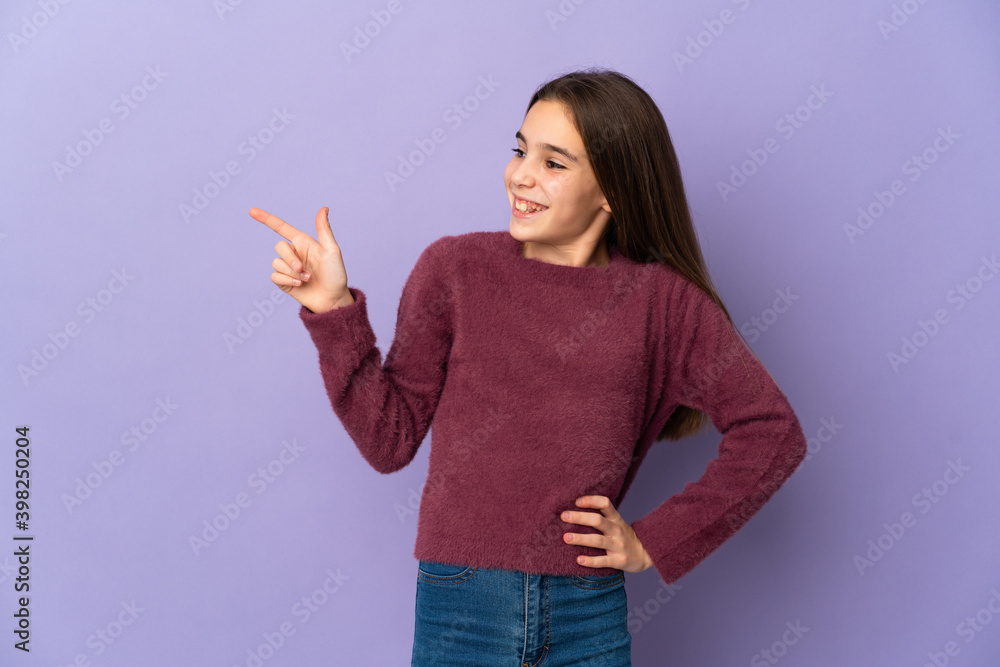 Little girl isolated on purple background pointing finger to the side and presenting a product Little girl isolated on purple background pointing finger to the side and presenting a product