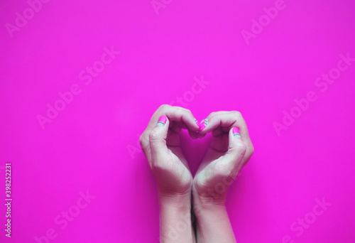 hands in the shape of a heart on a pink background