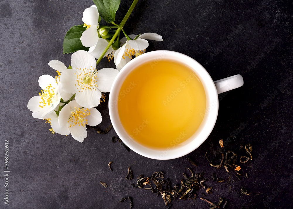 Jasmine flowers and cup of healthy tea on a black background. Top view. Herbal medicine Jasmine flowers and cup of healthy tea on a black background. Top view. Herbal medicine