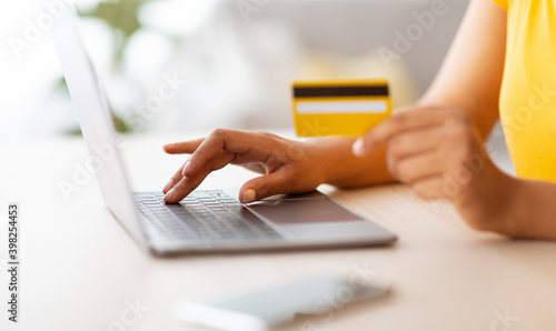 Black lady using laptop and debit credit card at home