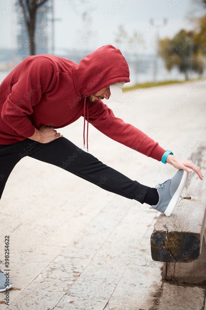 Athletic sporty man training in hoodie sweatshirt in urban city park. Athletic sporty man training in hoodie sweatshirt in urban city park.