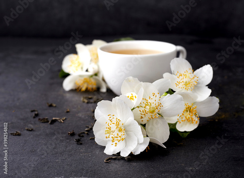 Jasmine flowers and cup of healthy tea  on a black background. Herbal medicine