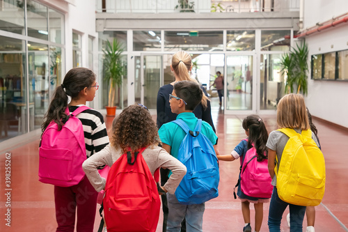 Foto Group of children with female teacher walking in school corridor