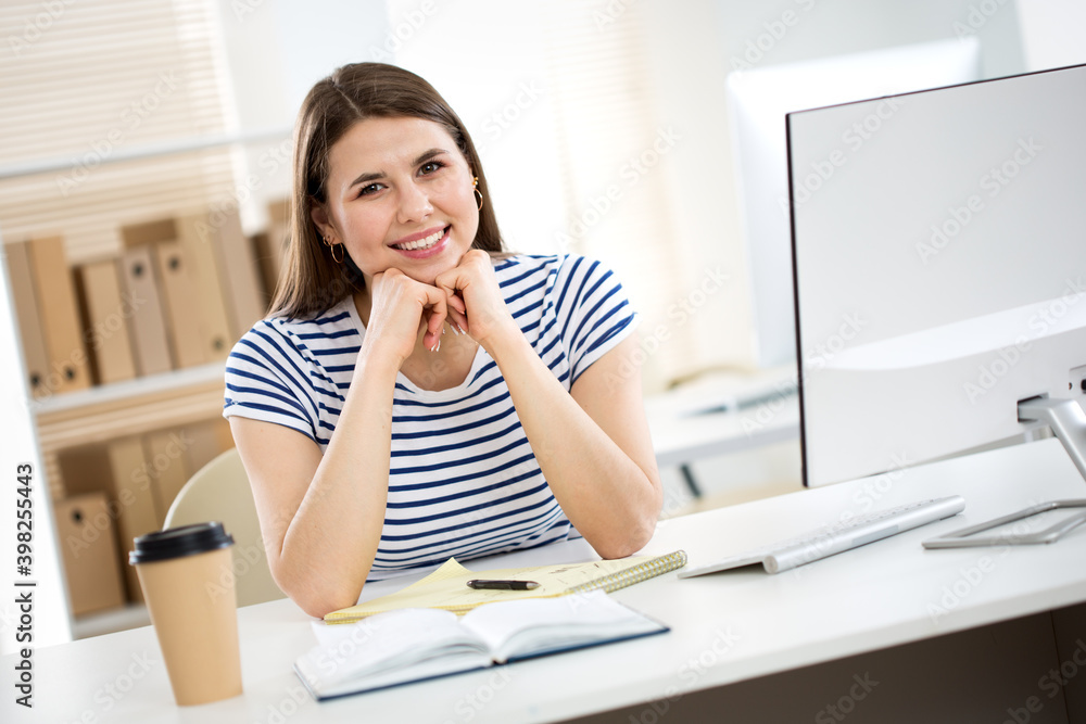 Portrait of business woman looking at camera at workplace in an office