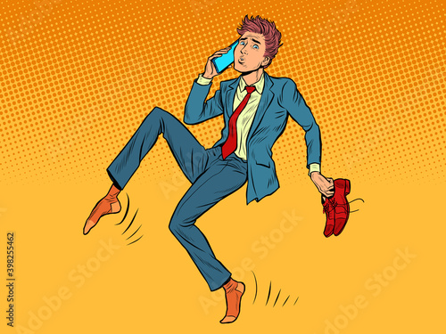 The man sneaks up quietly. Shoes in hand, talking on the phone
