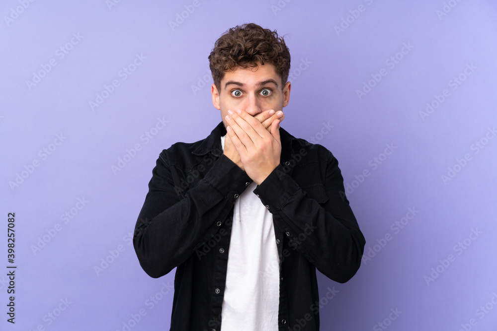 Caucasian man isolated on purple background covering mouth with hands Caucasian man isolated on purple background covering mouth with hands