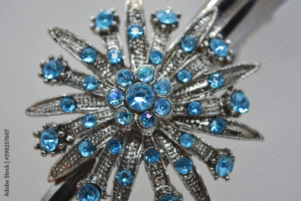 A large beautiful female metal jewelry with blue stones, engravings, an unusual shape is located on a white matte background. A large beautiful female metal jewelry with blue stones, engravings, an unusual shape is located on a white matte background.