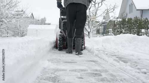 Cleaning snow from a driveway with snow blower machine