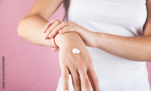 Young woman applying natural cream onto skin.