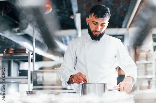 Chef in white uniform cooking food at kitchen. Busy day at work