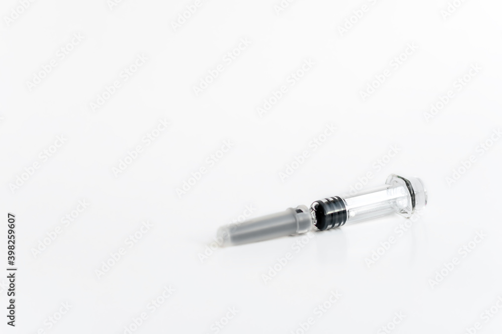 A syringe with a needle and a cap for medical vaccination on a light background lies on the table. copy space. A syringe with a needle and a cap for medical vaccination on a light background lies on the table. copy space.