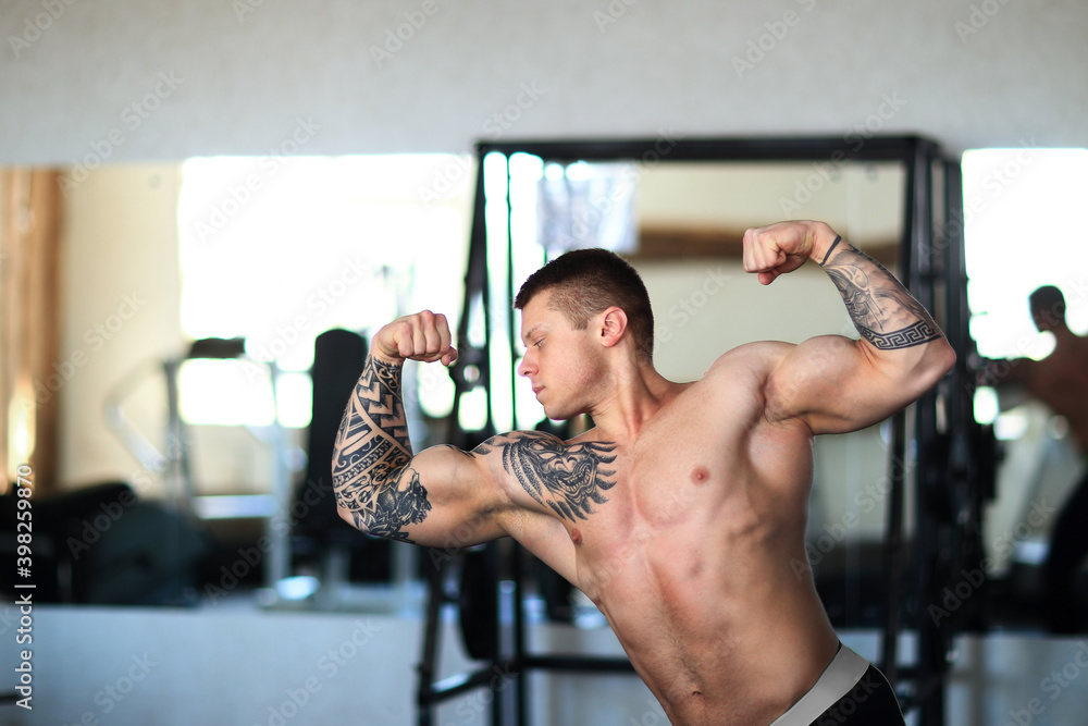 attractive young bodybuilder posing in a modern gym. attractive young bodybuilder posing in a modern gym.