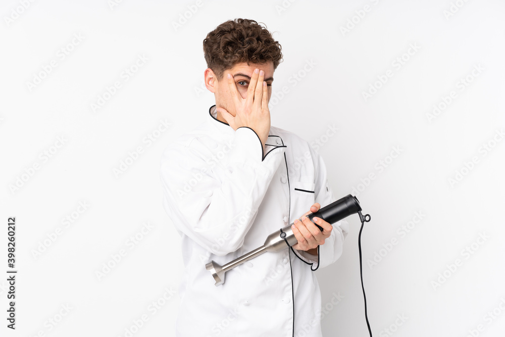 Man using hand blender isolated on white background covering eyes and looking through fingers Man using hand blender isolated on white background covering eyes and looking through fingers