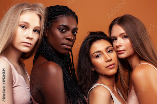 young pretty asian, caucasian, afro woman posing cheerful together on brown background, lifestyle diverse nationality people concept