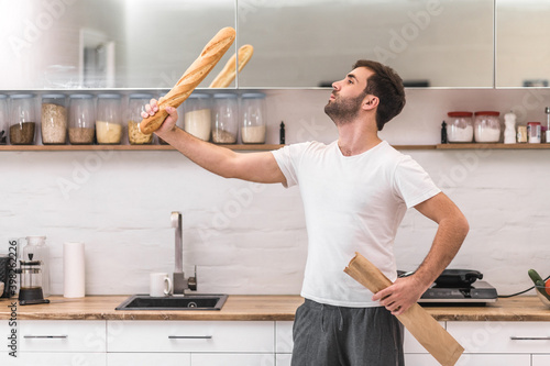 Handsome man posing for a photo with baguette in hand.