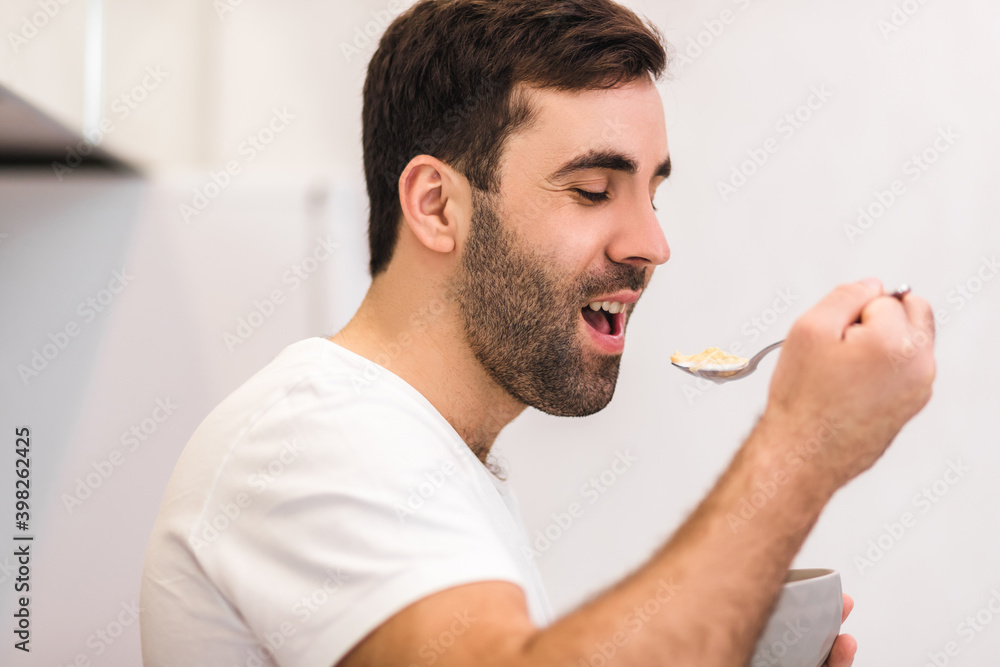 Photo of hungry young man eating breakfast from bowl. Photo of hungry young man eating breakfast from bowl.