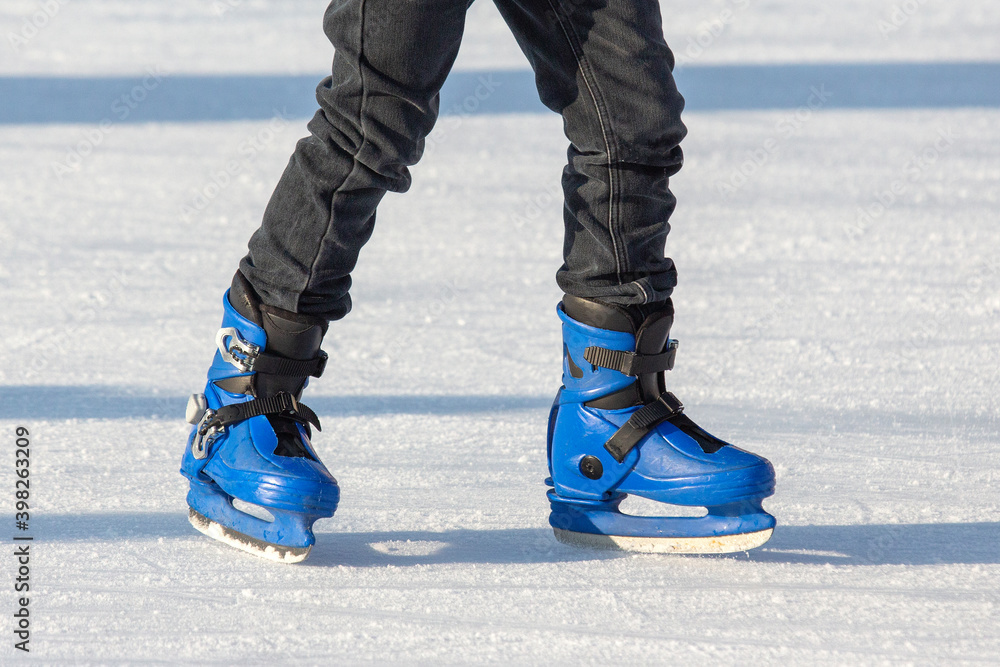 legs of a man in blue skates rides on an ice rink. hobbies and leisure. winter sports legs of a man in blue skates rides on an ice rink. hobbies and leisure. winter sports