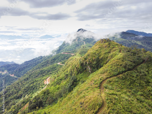 Beautiful green mountains with path road, cloud, and fog.