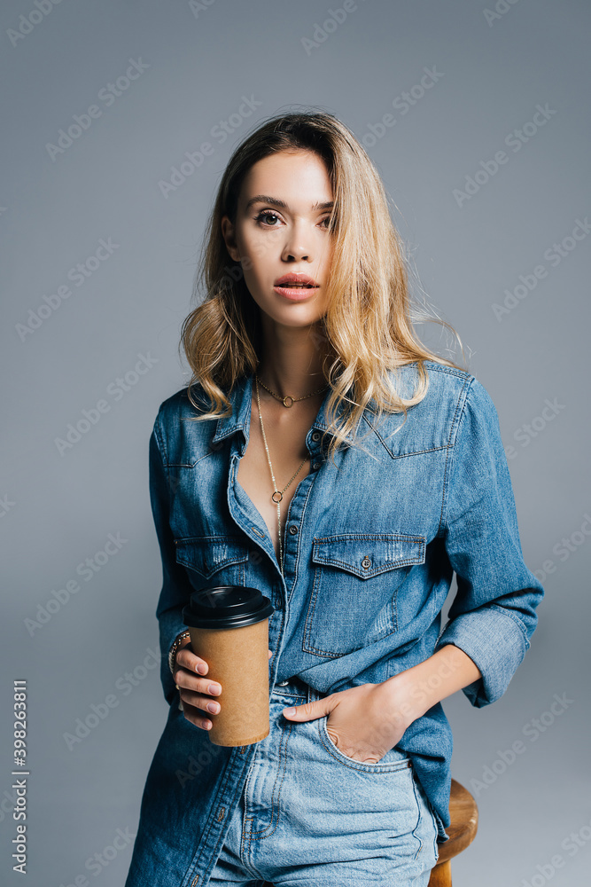 stylish woman in denim short, with hand in pocket, holding coffee to go isolated on grey stylish woman in denim short, with hand in pocket, holding coffee to go isolated on grey