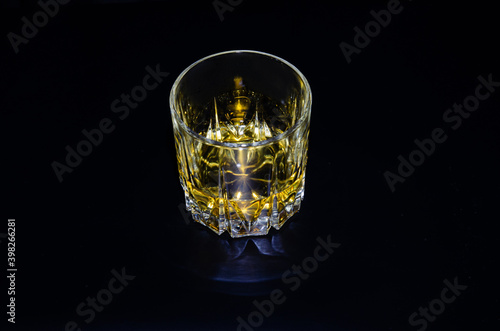 A glass of whiskey with ice on a black background. Copy the space.