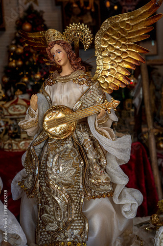 A Doll of Virgin Mary with wings and holding a musical instrument in a shop window. Saint woman as a symbol of love and kindness. Close-up