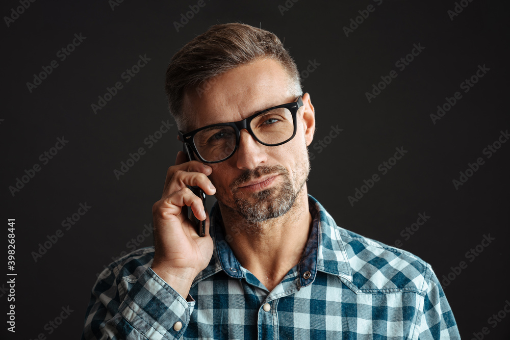 Fototapeta premium Serious grey-haired man talking by mobile phone
