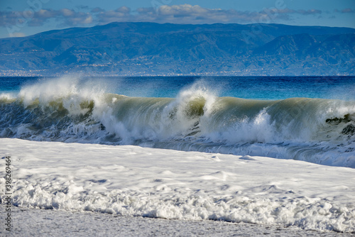 the sea stirred by the swirling wind forms large and noisy waves that crash on the shore with splashes and foam