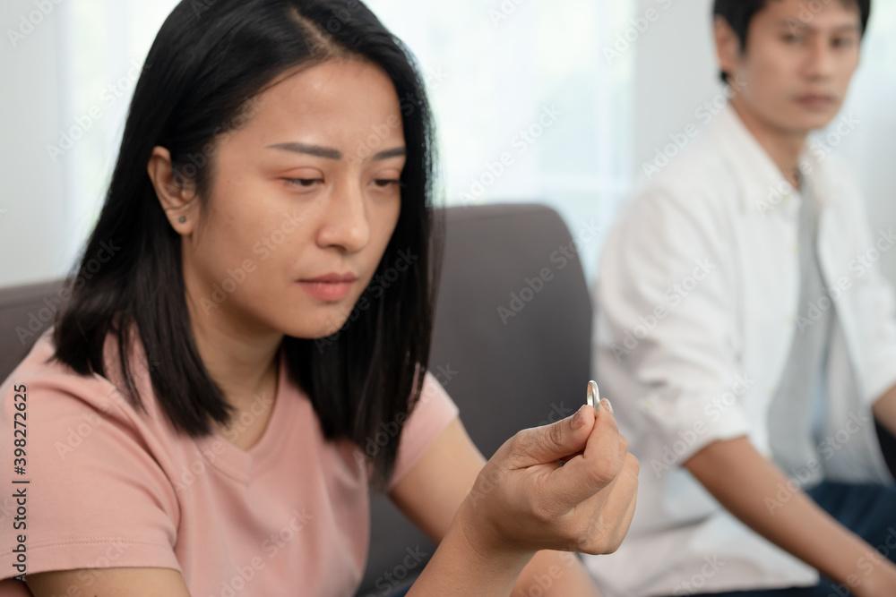 Unhappy young asian couples quarrel on the couch, relationships are in trouble. The wife holding the wedding ring in disappointment and upset for her husband, which may lead to divorce. Unhappy young asian couples quarrel on the couch, relationships are in trouble. The wife holding the wedding ring in disappointment and upset for her husband, which may lead to divorce.