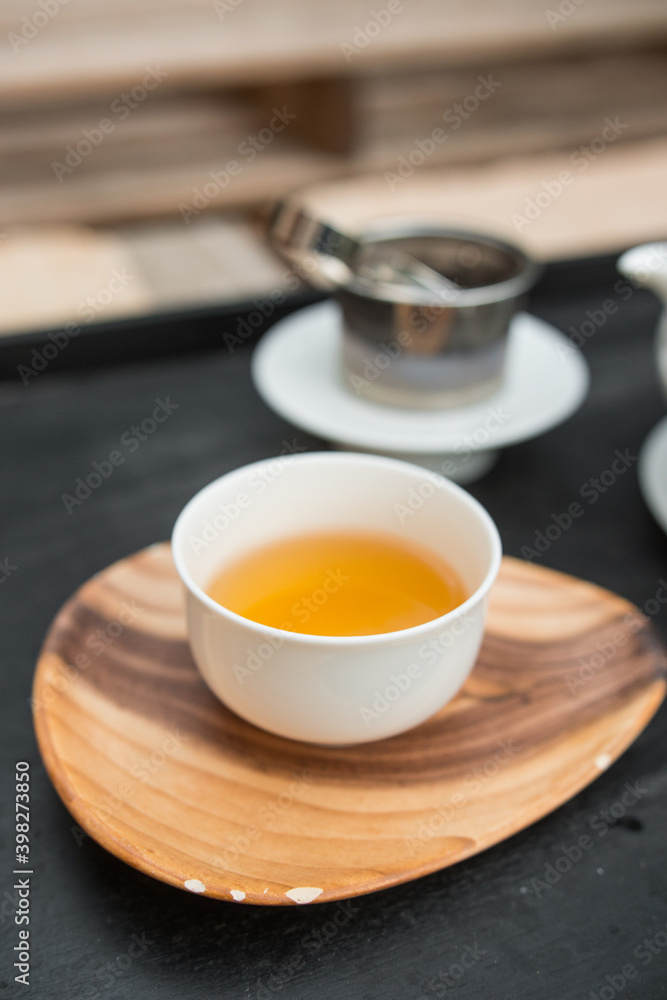 White porcelain tea cup. 
Fresh natural Qilan tea from Fujian province, a rolled oolong. Beautiful orange color. Vertical shot.