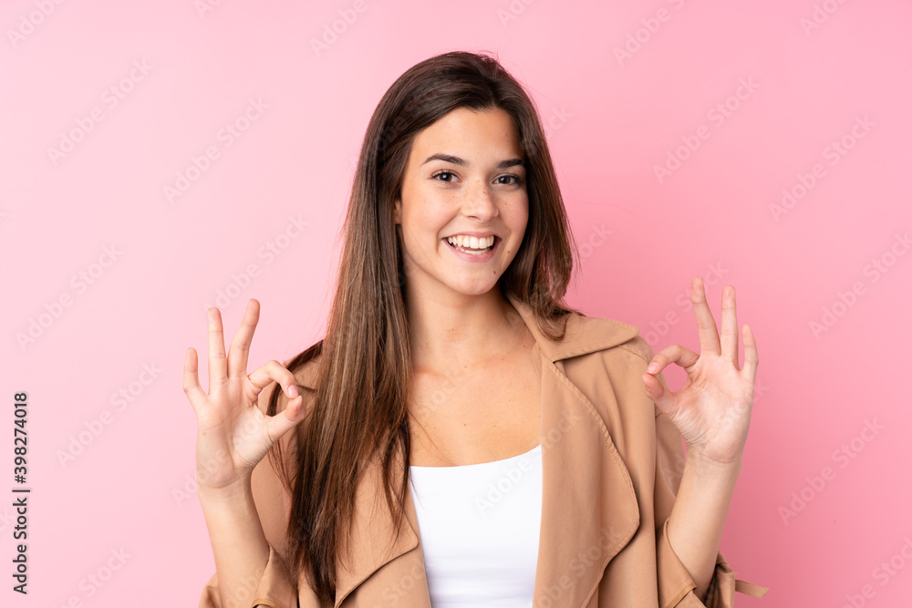 Teenager Brazilian girl over isolated pink background showing an ok sign with fingers Teenager Brazilian girl over isolated pink background showing an ok sign with fingers