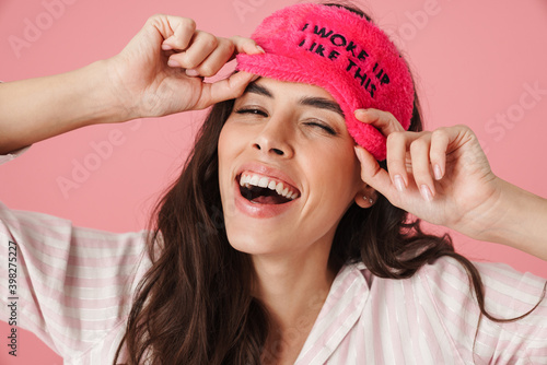 Happy beautiful woman laughing while posing in sleeping mask