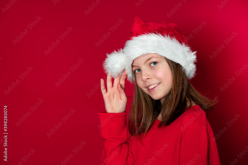 pretty young girl with Santa Claus cap and red pullover in front of red background pretty young girl with Santa Claus cap and red pullover in front of red background