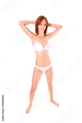 Young laughing woman wearing white bra and panties, full length portrait isolated in front of white studio background