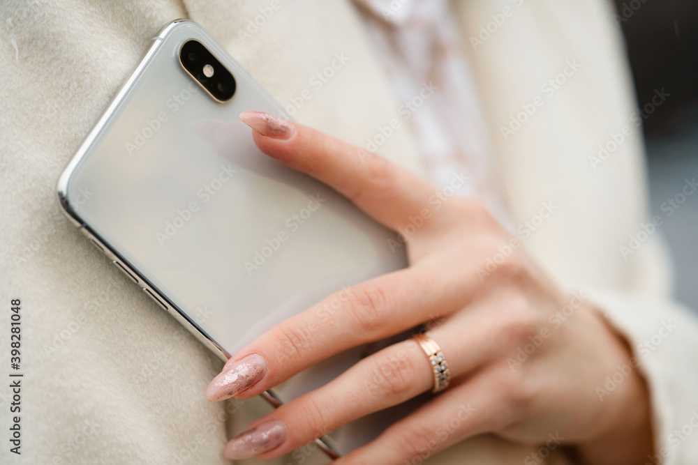 hands of a girl with a phone in her hands.