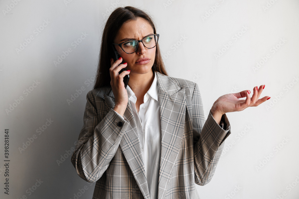 Beautiful brooding businesswoman in eyeglasses talking on cellphone Beautiful brooding businesswoman in eyeglasses talking on cellphone