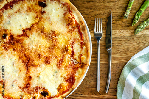 Quattro Formaggi pizza with mozzarella, parmiggiano,  provolone and gorgonzola dolce served on a wooden table in trattoria italiana photo