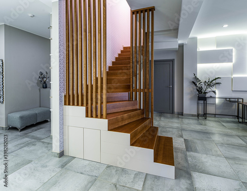 Contemporary interior of luxury apartment. Modern design of wall. Wooden staircase.