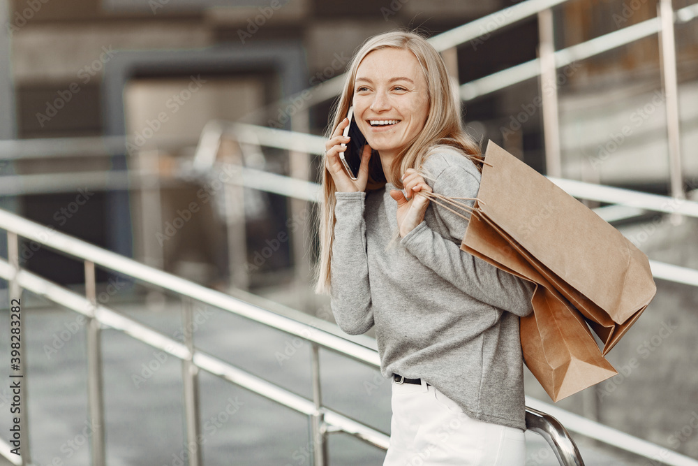 Fototapeta premium Woman in a summer city. Lady with mobile phone. Woman in a gray sweater.