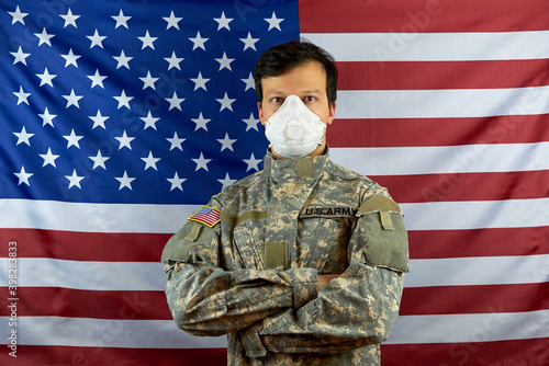 A soldier in a respirator. American soldier wearing a protective mask against COVID-19 on the background of the American flag