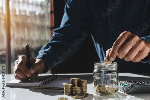 Business man putting coin in glass bottle saving bank and account for his money all in finance accounting concept.