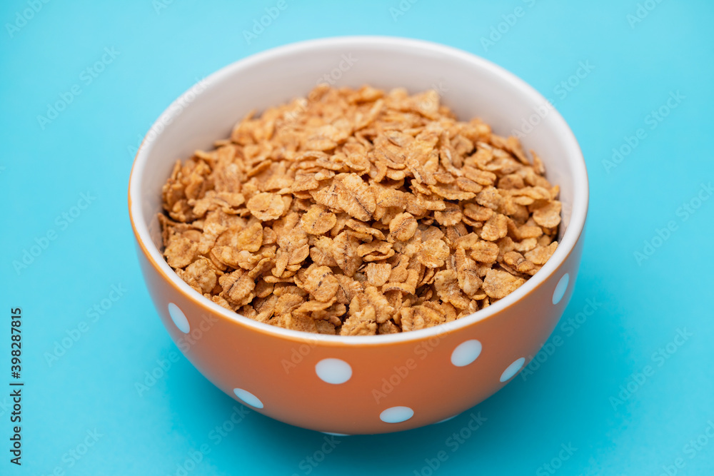flakes wheat in the bowl on blue background flakes wheat in the bowl on blue background